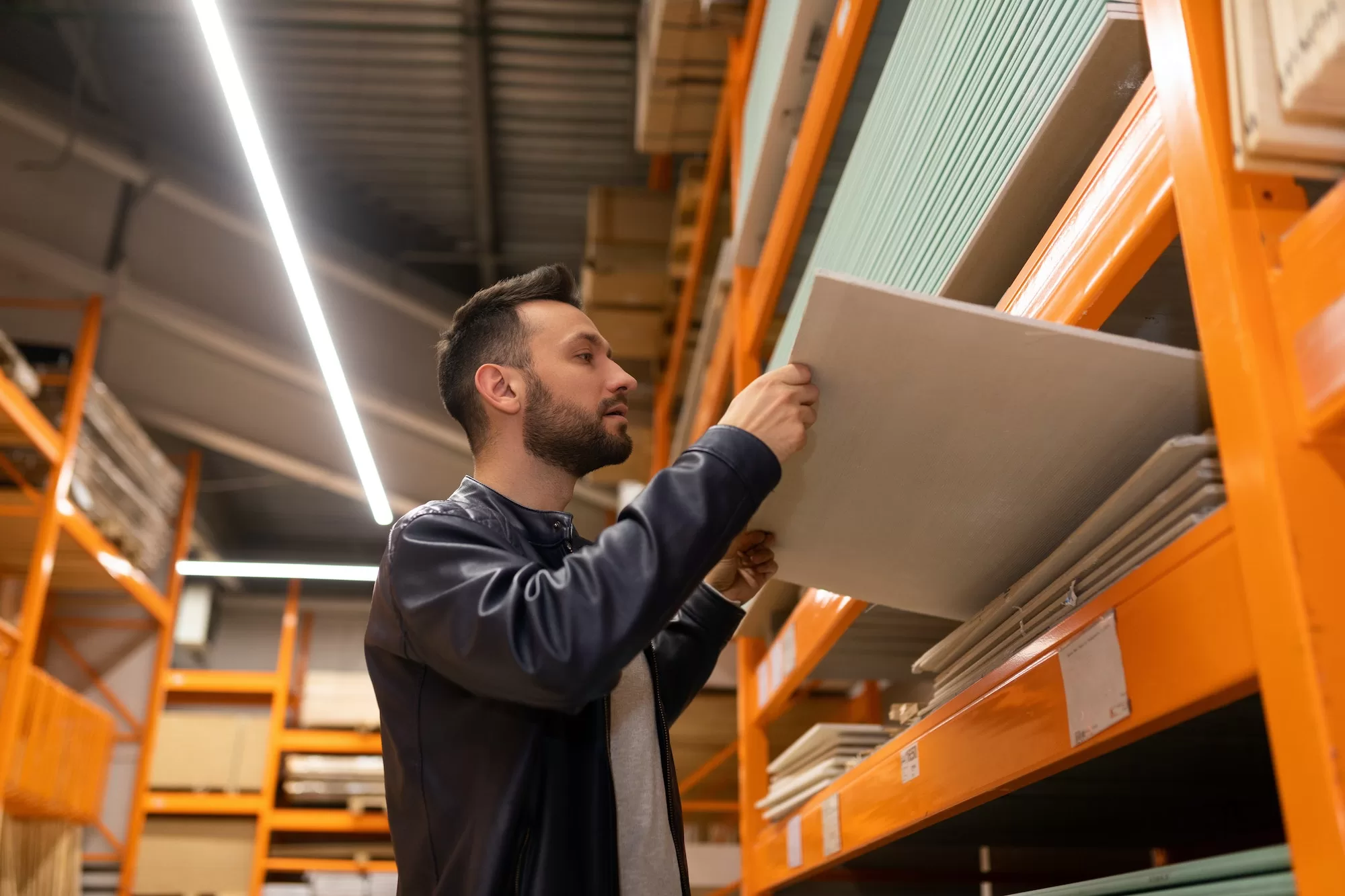 a man in a construction hypermarket chooses materials for wall decoration examines OSB boards and
